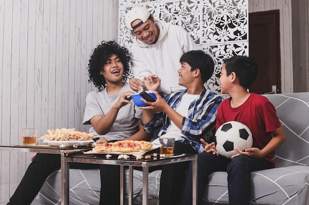 les amateurs de sport dégustant des aliments et des boissons ensemble tout en regardant un match de football à la télévision