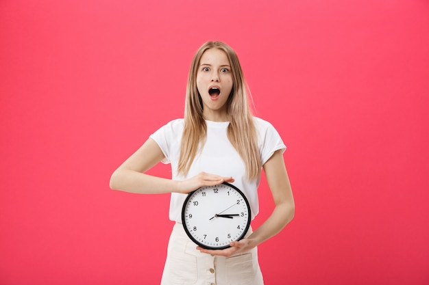 Amazing femme tenant une horloge. Femme surprise en t-shirt blanc avec horloge noire