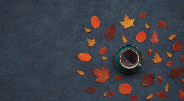 Ambiance d'automne fond d'automne Une tasse de café et des feuilles d'automne lumineuses sur fond sombre Vue de dessus avec espace de copie