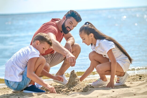 Ambiance créative. Un père avec des enfants qui fait des châteaux de sable
