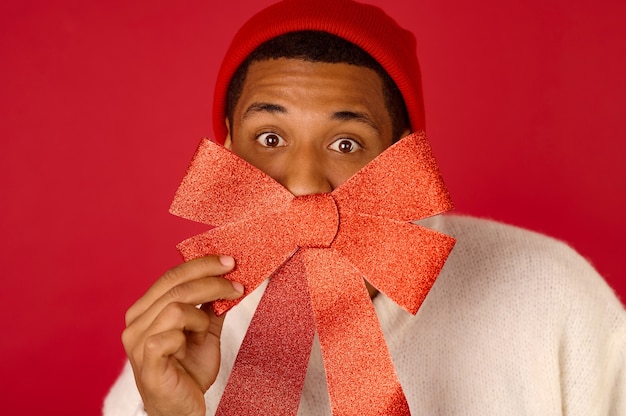 Ambiance festive. Un jeune homme à la peau foncée en bonnet de Noel se sentant joyeux