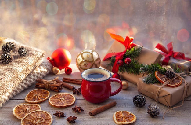 Ambiance de Noël atmosphère de vacances tasse de café rouge coffrets cadeaux de Noël sapin de Noël boule dorée cônes anis étoilé cannelle sur un rebord de fenêtre en bois