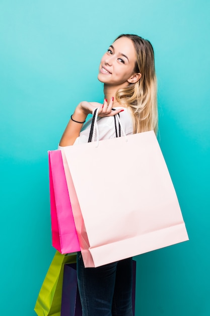 Ambiance shopping colorée. Portrait de pleine longueur de femme blonde souriante avec des sacs colorés sur le mur de menthe