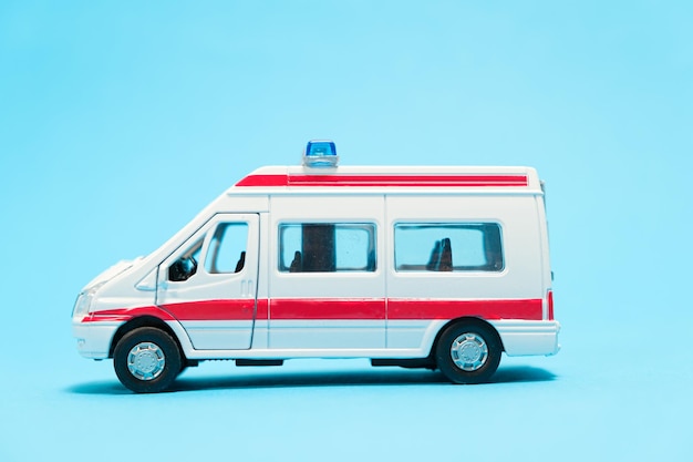 Une ambulance jouet blanche avec des lignes rouges sur fond bleu