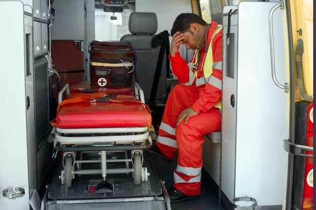 Photo ambulancier fatigué plein coup dans une voiture d'ambulance