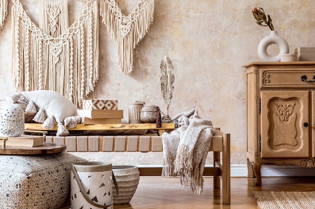 Aménagement intérieur d'un salon élégant avec chaise longue beige, oreillers, lanterne, macramé, fleur séchée, théière sur le plateau, décoration et accessoires personnels élégants dans un concept oriental.