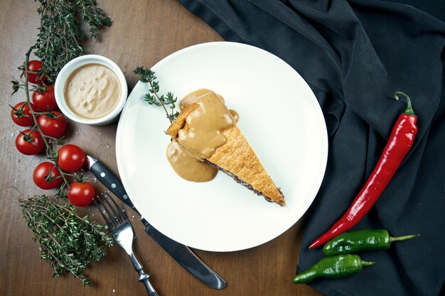 Américain classique morceau de tarte au boeuf fumeur - poitrine de sauce aux arachides sur une plaque blanche dans une composition avec des légumes. Pâtisserie savoureuse.