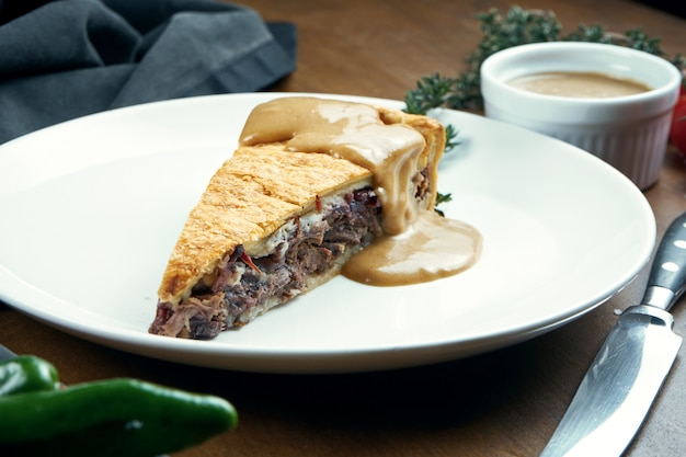 Américain classique morceau de tarte au boeuf fumeur - poitrine de sauce aux arachides sur une plaque blanche dans une composition avec des légumes. Pâtisserie savoureuse.