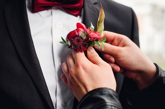 Ami met une boutonnière sur le costume de marié