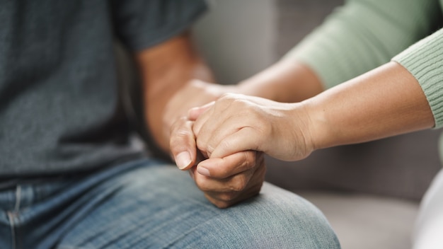 Amie ou famille assise et se tenant la main pendant qu'elle encourage l'homme dépressif mental, la psychologue fournit une aide mentale au patient. Concept de santé mentale TSPT