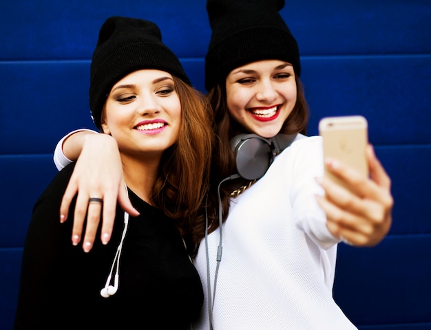 Amies adolescentes à l'extérieur font selfie sur un téléphone.