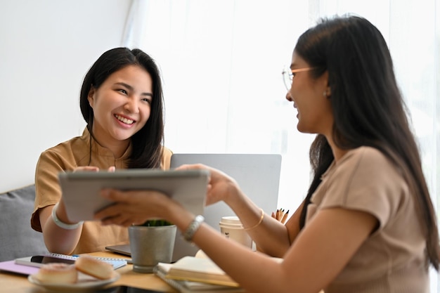 Des amies asiatiques se détendant aiment parler et regarder ensemble une tablette numérique