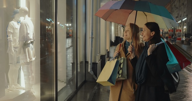 Les amies devant les magasins montrent la fenêtre