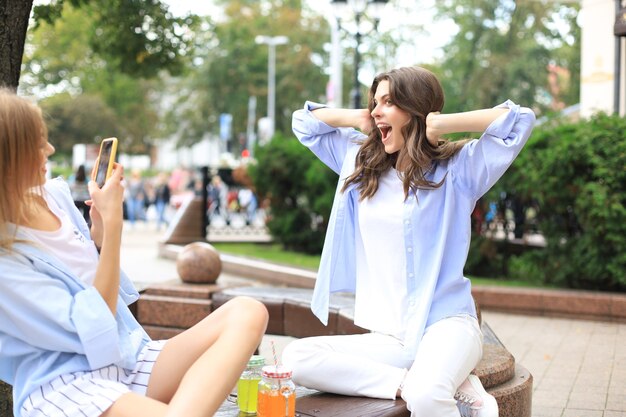 Des amies heureuses se prennent en photo sur un banc dans la ville.