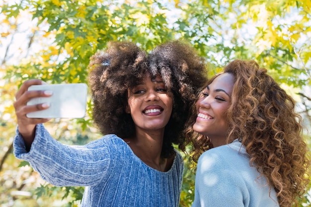 Photo des amies joyeuses se font des selfies à l'extérieur.