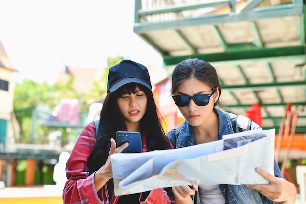 Photo des amies lisant une carte en se tenant debout en ville