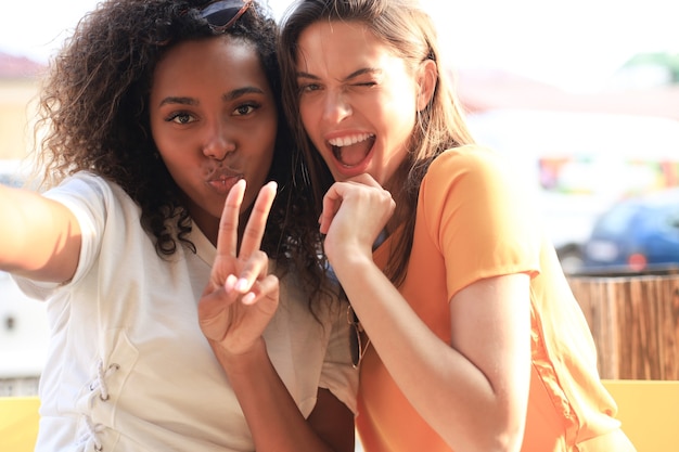 Amies mignonnes de jeunes filles s'amusant ensemble, prenant un selfie assis au café.