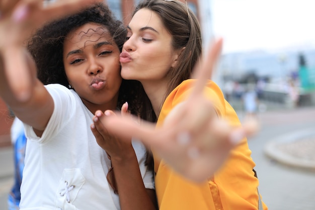 Amies mignonnes de jeunes filles s'amusant ensemble, prenant un selfie à la ville.
