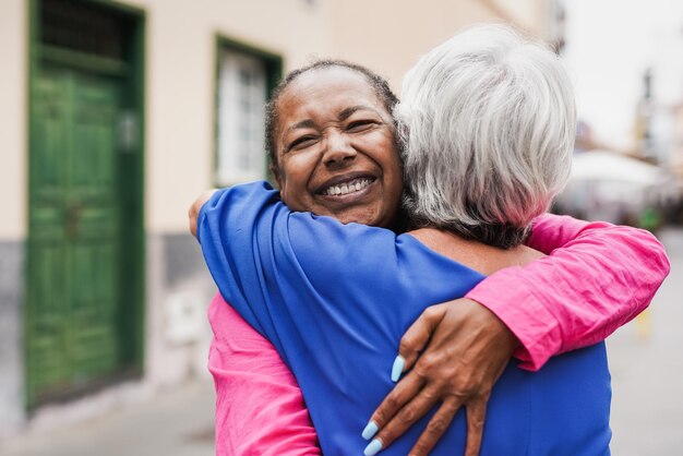 Amies multiraciales âgées se rencontrant et s'embrassant dans la ville