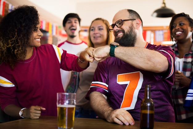 Amis acclamant le sport au bar ensemble