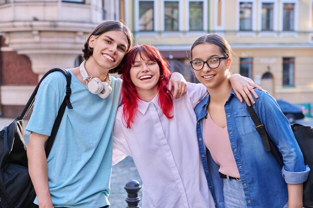 Amis adolescents heureux souriants s'embrassant en regardant la caméra à l'extérieur dans la rue de la ville Communauté d'amitié Mode de vie de la jeunesse Loisir concept amusant