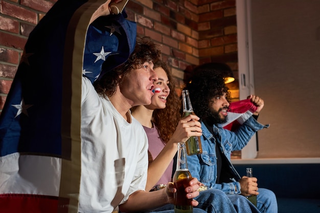 Des amis américains boivent de la bière tout en encourageant leur équipe préférée au championnat de football à la télévision, de jeunes étudiants crient, hurlent, célèbrent la victoire