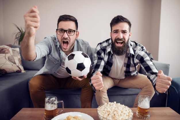 Amis appréciant le football à la télévision