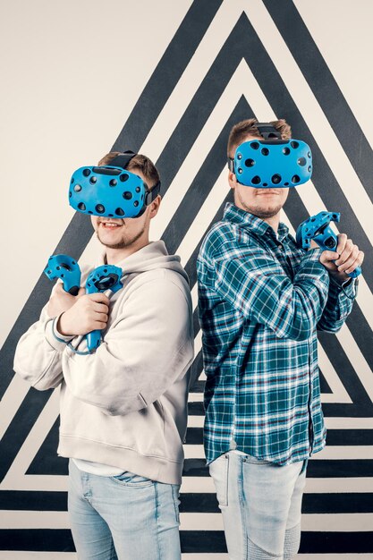 Des amis apprécient la technologie VR, deux gars portent un casque VR et jouent. Concept de gadget futuriste.