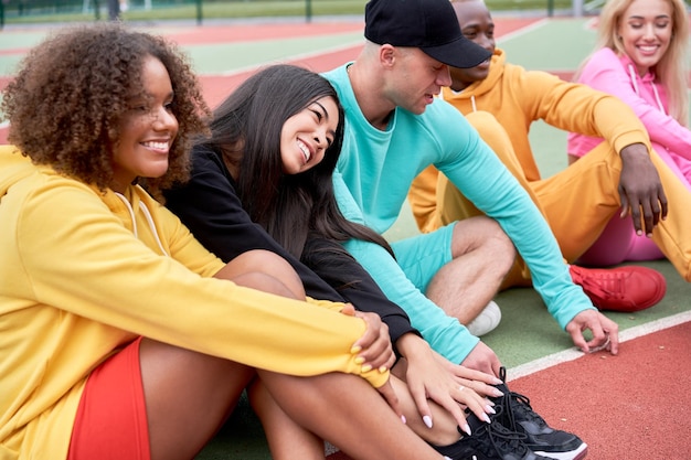 Photo des amis assis sur un terrain de sport contre le ciel