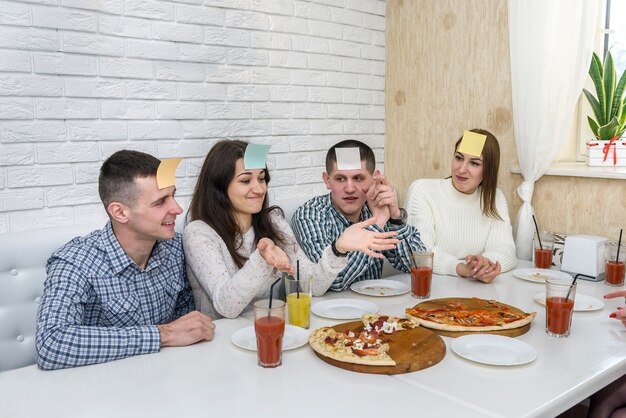 Des amis au café mangent de la pizza et jouent à deviner qui