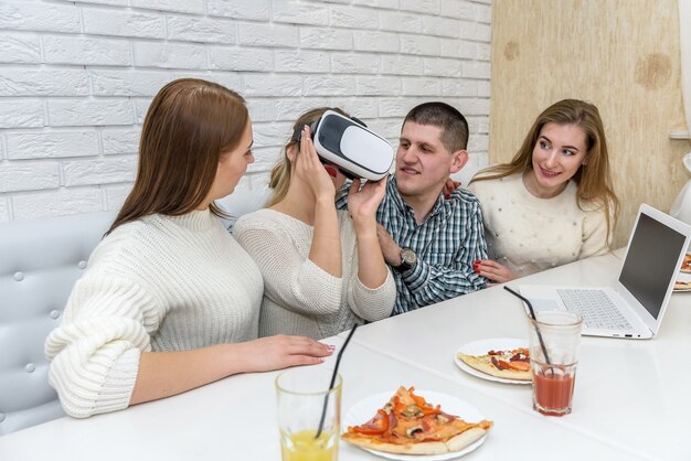 Amis au café manger de la pizza et essayer des lunettes virtuelles 3d