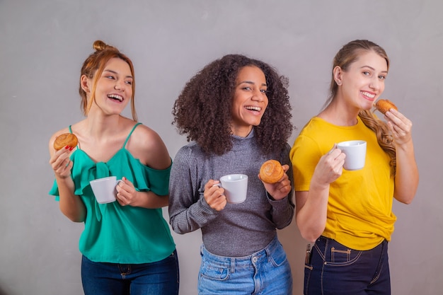 Amis au thé de l'après-midi mangeant des beignets et buvant du café avec du lait