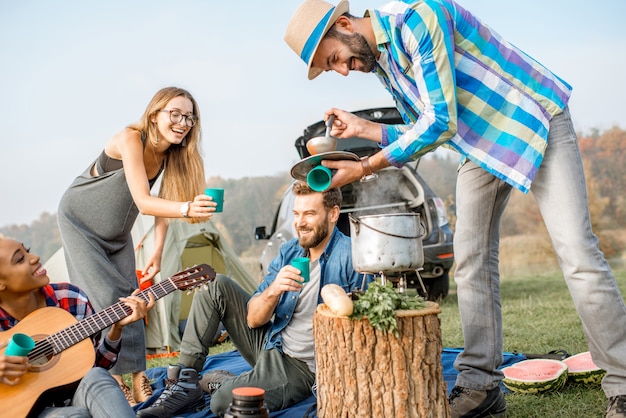 Amis ayant un délicieux dîner avec une soupe cuite au chaudron pendant le pique-nique au camping