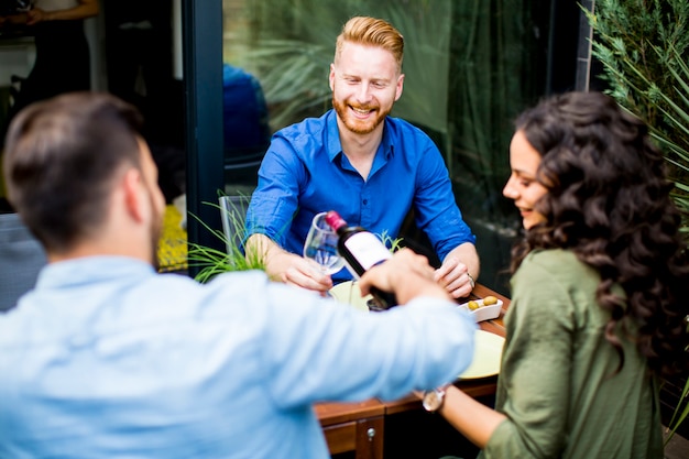 Amis ayant une fête de jardin en plein air et boire du vin rouge