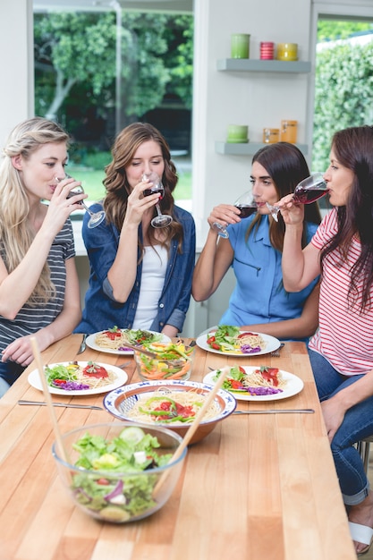 Amis ayant un verre de vin rouge pendant le repas sur la table