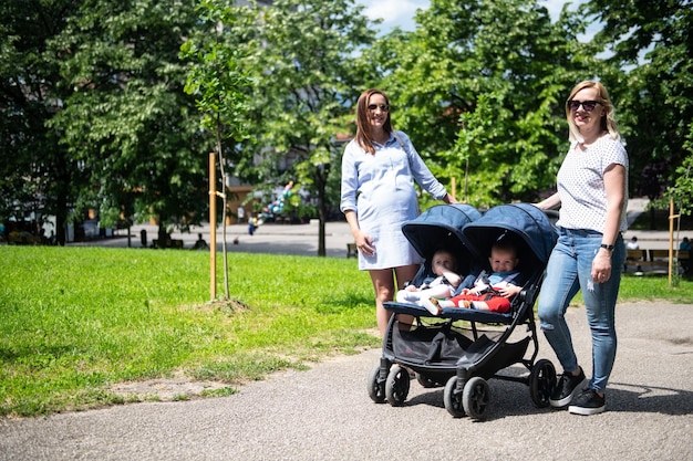 Amis avec des bébés poussette promenades dans le parc