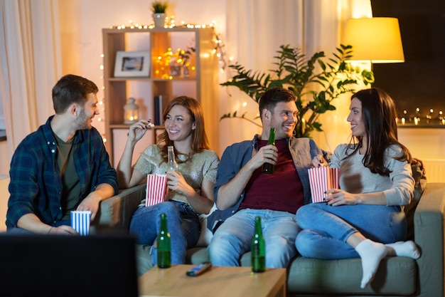 des amis avec de la bière et du pop-corn en train de regarder la télévision à la maison