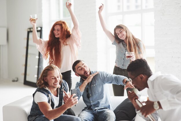 Les amis de bureau passent du bon temps assis et allongés sur le canapé blanc