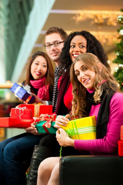 Amis avec des cadeaux de Noël et des sacs dans le centre commercial