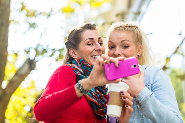 Amis avec café et téléphone en ville