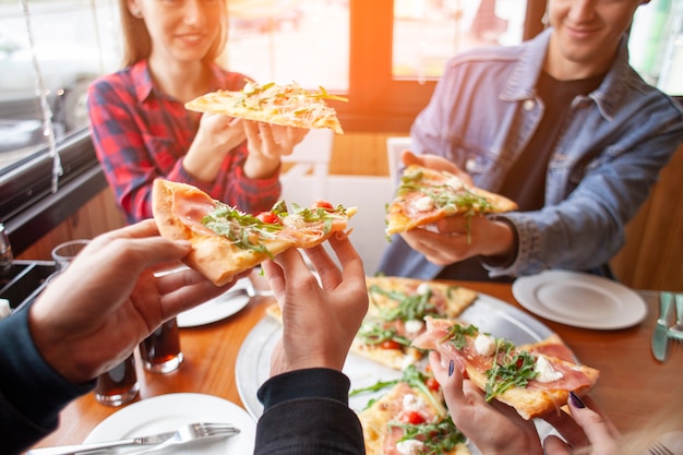 Les amis des camarades de classe mangent de la pizza dans une pizzeria, les élèves au déjeuner mangent de la restauration rapide