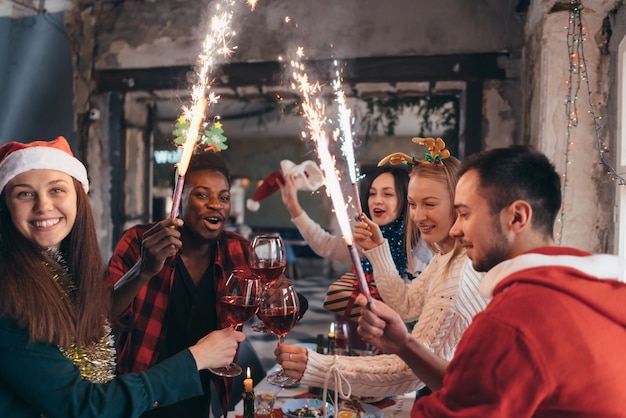 Amis avec des cierges magiques en mains. Groupe d'amis célébrant ensemble la veille de Noël.