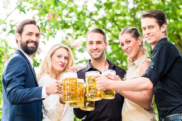 Amis ou collègues sur le jardin de la bière après le travail de grillage avec des boissons