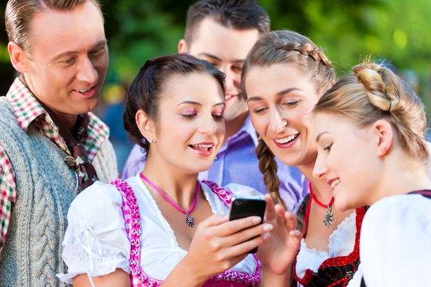 Amis dans le jardin de bière avec smartphone