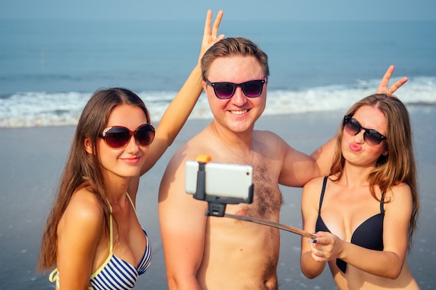 Des amis drôles font une photo sur un autocollant sur la plage