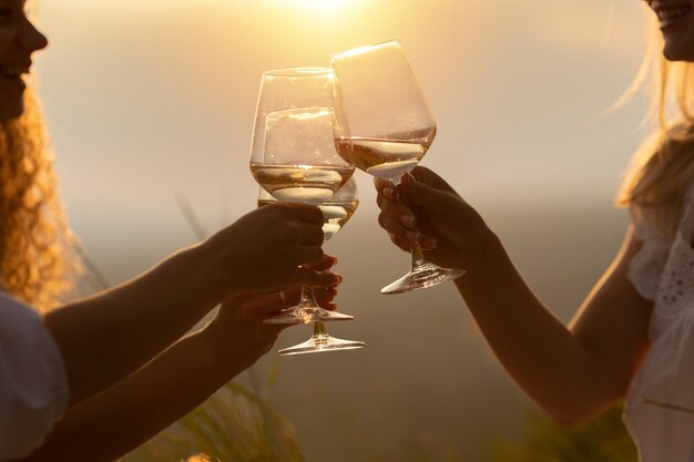 Photo amis avec du vin blanc dans les mains qui tintent avec des verres