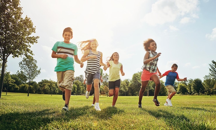 Photo amis enfants heureux et courir avec le champ d'herbe dans la nature pour un jour de jeu amusant ou le soleil au parc diversité ou un groupe d'enfants ou de jeunes excités appréciant des vacances ensoleillées en plein air ou un week-end ensemble