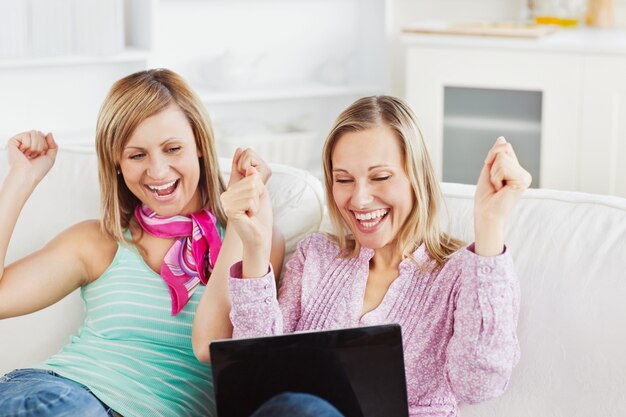 Des amis enthousiastes avec les bras en regardant l&#39;ordinateur portable