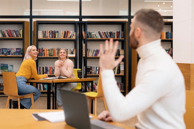 Photo amis étudiant à l'aide d'un ordinateur portable et de livres dans une bibliothèque