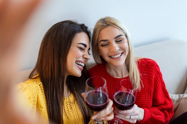 Amis excités prenant selfie et riant Photo intérieure de deux filles caucasiennes émotionnelles Deux femmes adultes faisant des selfies avec des grimaces Deux amies prenant un selfie